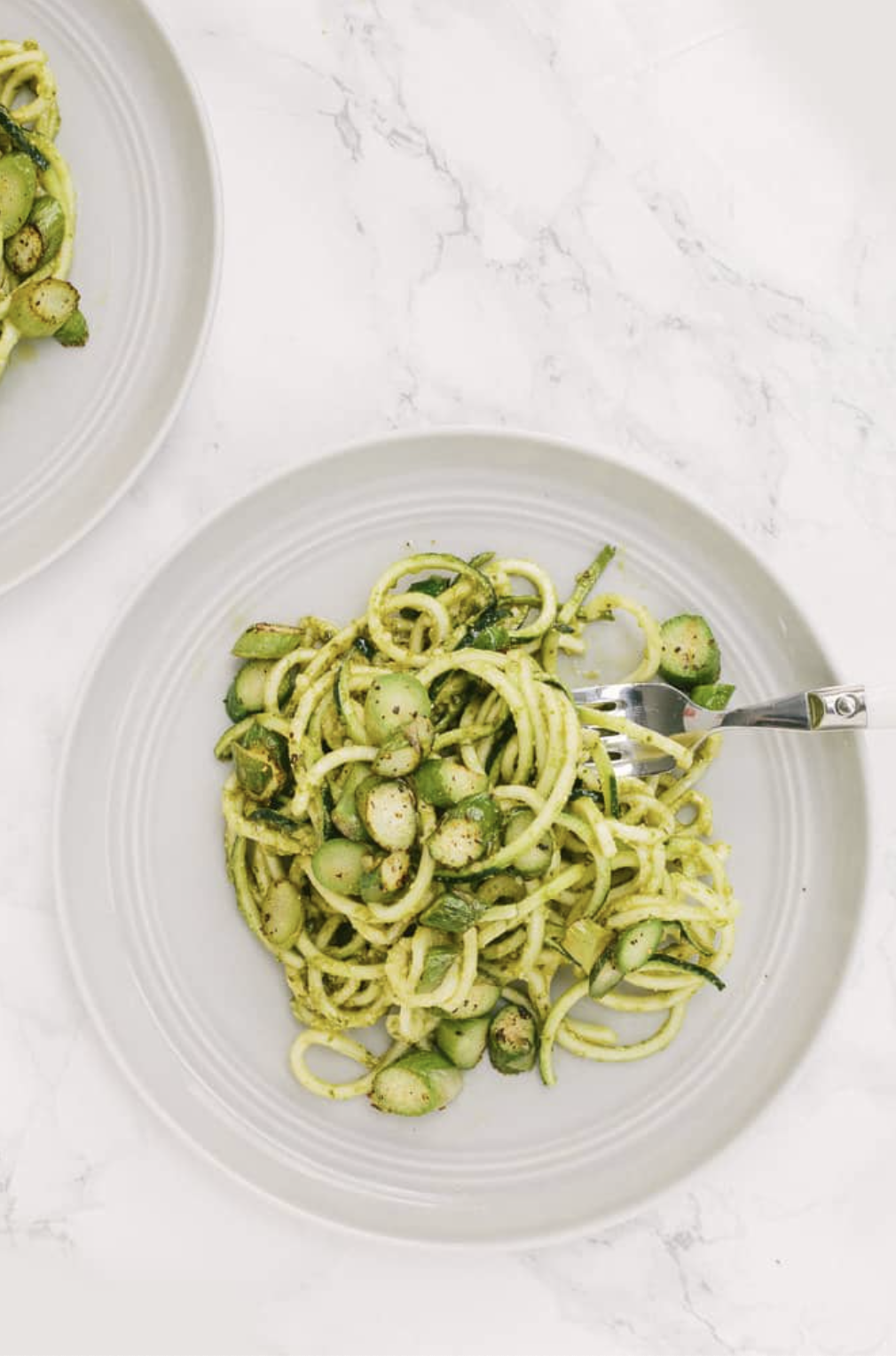 overhead of a white plate with green zucchini noodles